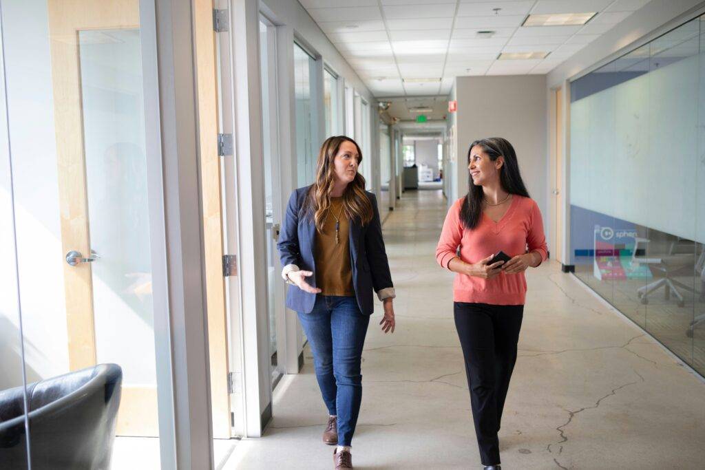 Two women walking and talking at work.