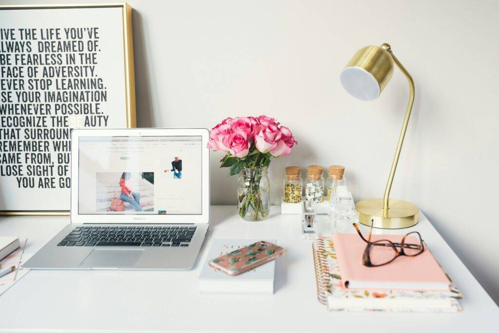 A desk with laptop, glasses, lamp