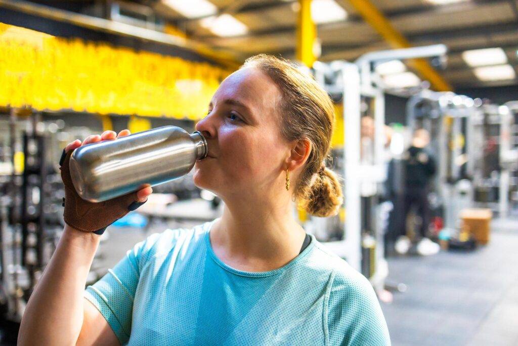 woman drinking water at gym GLP-1 weight loss experience fitness routine